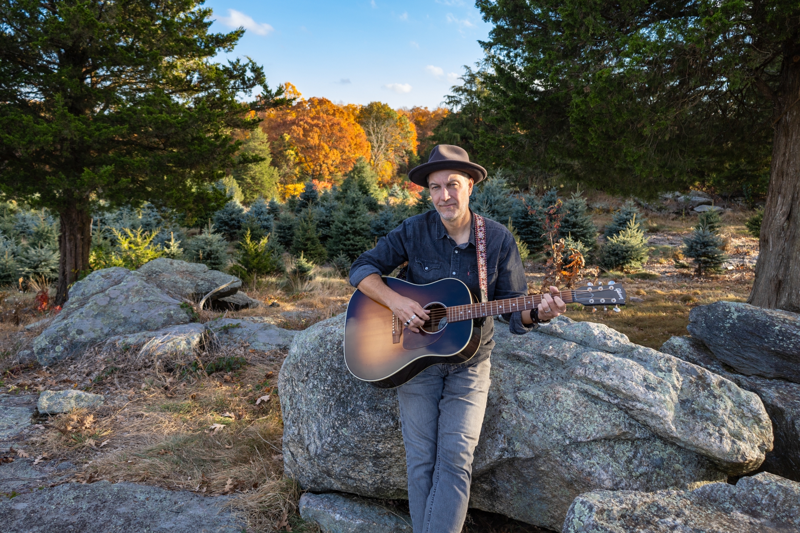 Brian Dolzani sitting on farm rocks in the fall