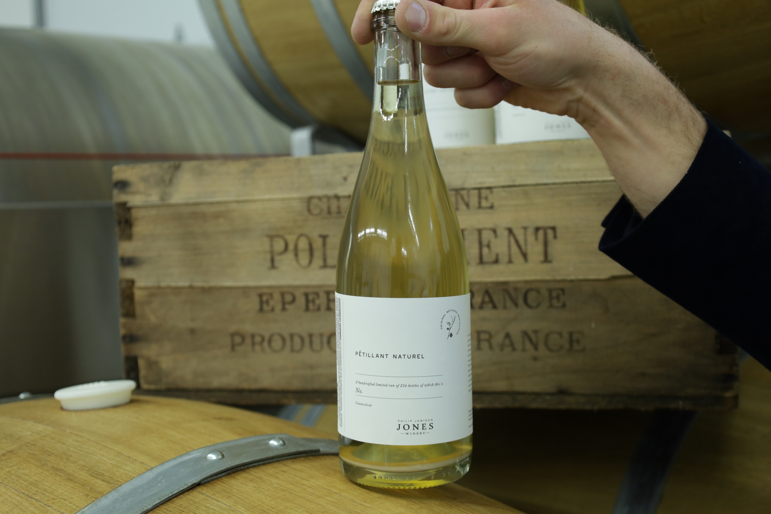 Winemaker holding a bottle of pet nat sparkling wine.